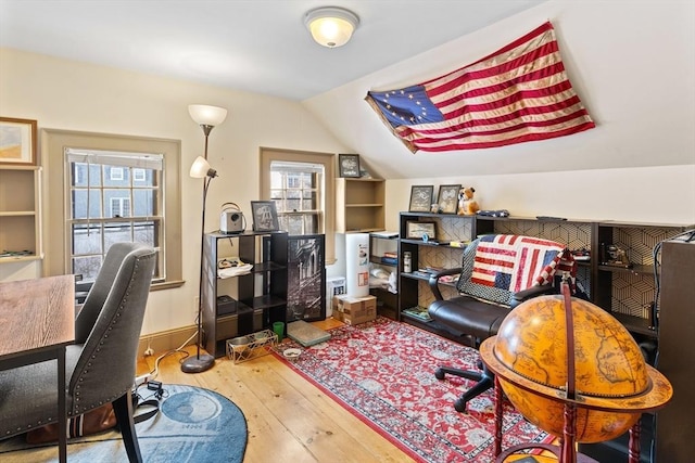 office with built in shelves, vaulted ceiling, and light hardwood / wood-style flooring