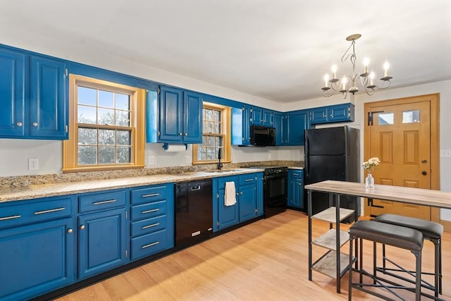 kitchen with blue cabinetry, a chandelier, pendant lighting, light hardwood / wood-style floors, and black appliances