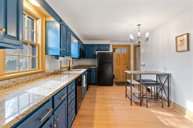 kitchen with pendant lighting, blue cabinets, sink, light stone counters, and black appliances