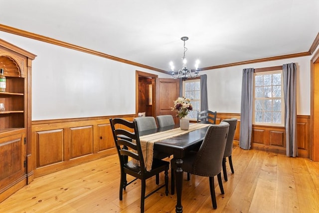 dining room with crown molding, light hardwood / wood-style flooring, and a notable chandelier