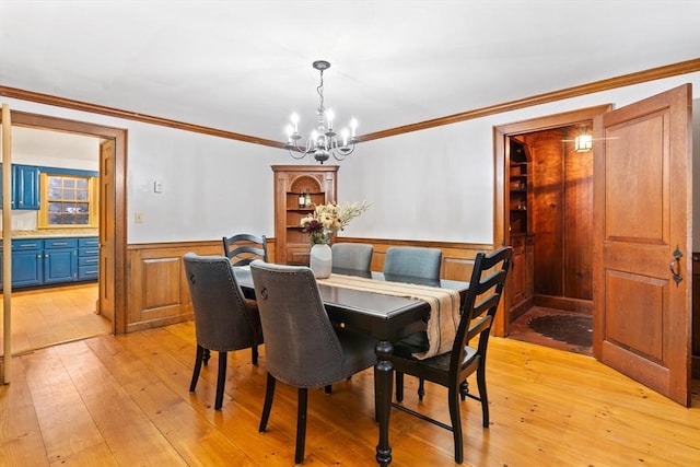 dining space with ornamental molding, a notable chandelier, and light hardwood / wood-style floors