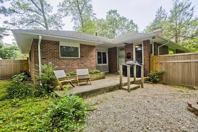 115 Carnavon Cir, Springfield, MA 01109 - back of property with brick siding, a chimney, a fenced backyard, and a patio