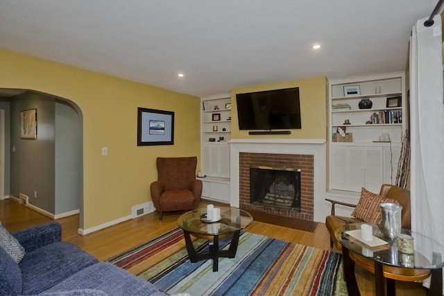 115 Carnavon Cir, Springfield, MA 01109 - living room featuring arched walkways, a fireplace, wood finished floors, recessed lighting, and built in features