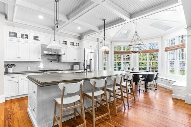25 Wedgemere Ave, Winchester, MA 01890 - kitchen with coffered ceiling, dark countertops, built in refrigerator, wall chimney range hood, and decorative backsplash