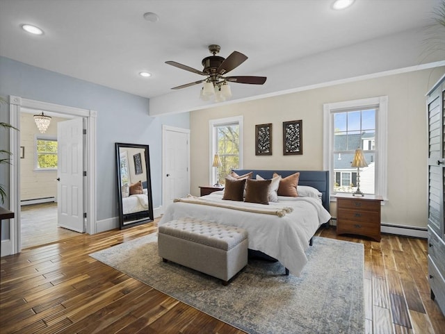 bedroom with a baseboard radiator, baseboard heating, multiple windows, and hardwood / wood-style flooring