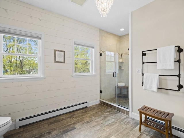 full bath with a notable chandelier, toilet, a shower stall, wood finished floors, and a baseboard radiator