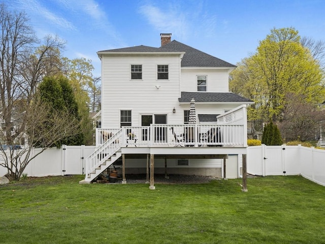 rear view of property featuring a lawn, a wooden deck, a gate, stairway, and a fenced backyard