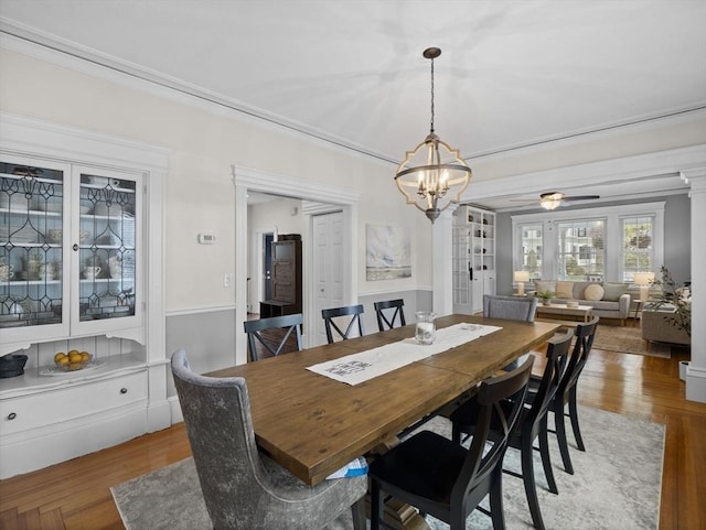 dining room featuring light wood-type flooring, ornamental molding, and ceiling fan with notable chandelier