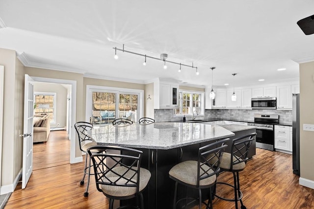 kitchen featuring a kitchen bar, a kitchen island, appliances with stainless steel finishes, and crown molding