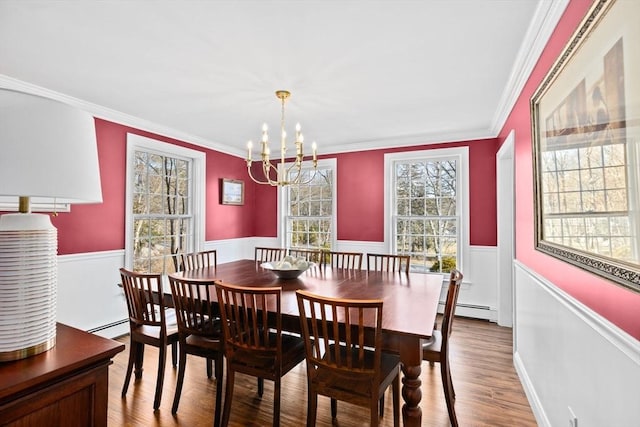 dining room featuring crown molding, baseboard heating, wood finished floors, and wainscoting