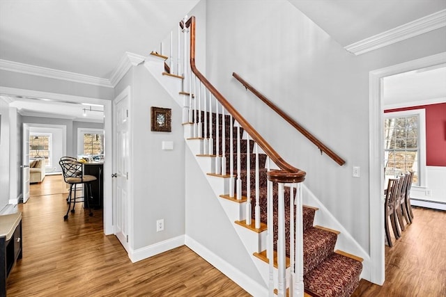 stairs featuring baseboards, plenty of natural light, wood finished floors, and crown molding