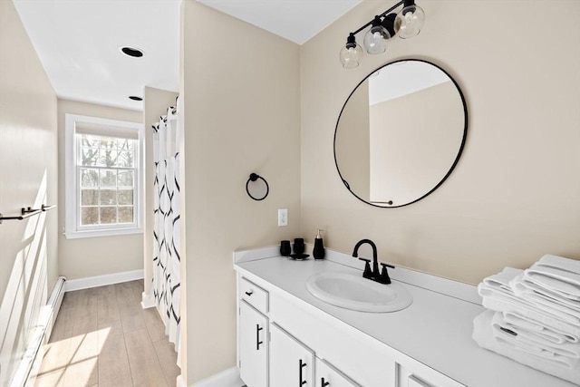 full bathroom featuring baseboards, wood finished floors, and vanity