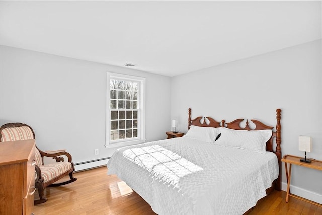 bedroom featuring a baseboard radiator, visible vents, and wood finished floors