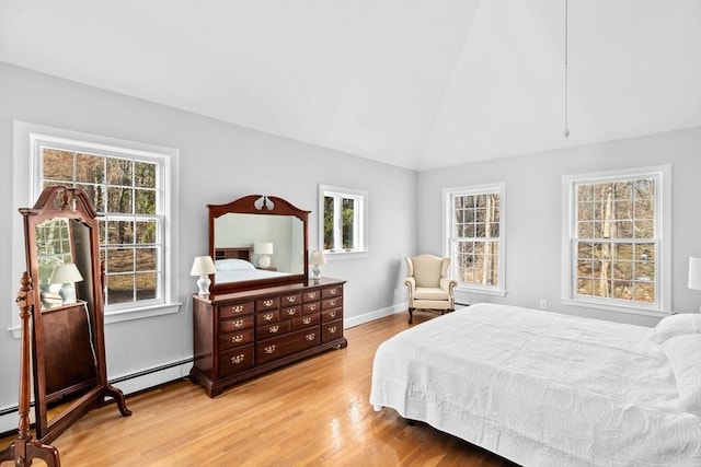 bedroom with vaulted ceiling, light wood finished floors, a baseboard radiator, and baseboards