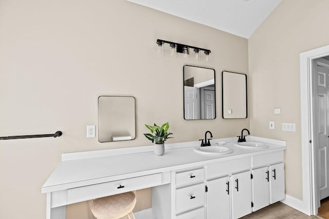 bathroom with wood finished floors, a sink, baseboards, and double vanity