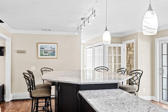 kitchen featuring dark cabinets, crown molding, a breakfast bar, and dark wood finished floors