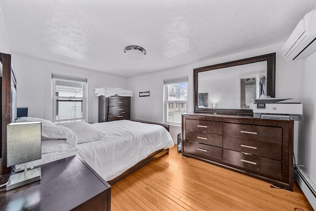 11 Murphy Ct, Newton, MA 02458 - bedroom with a baseboard radiator, an AC wall unit, light wood-style floors, and a textured ceiling