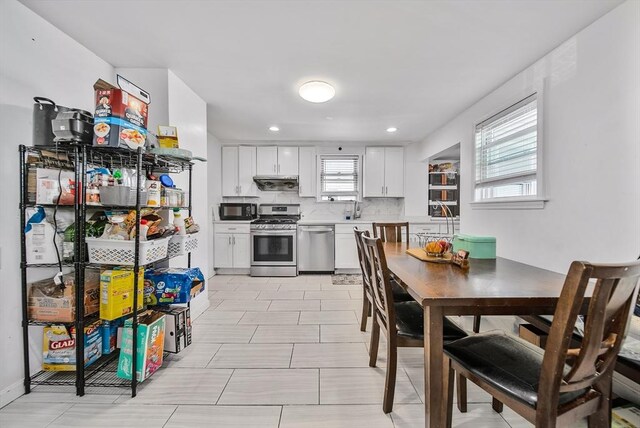 11 Murphy Ct, Newton, MA 02458 - kitchen featuring stainless steel appliances, range hood, white cabinetry, light countertops, and tasteful backsplash
