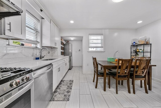 11 Murphy Ct, Newton, MA 02458 - kitchen with a sink, appliances with stainless steel finishes, ventilation hood, backsplash, and white cabinetry