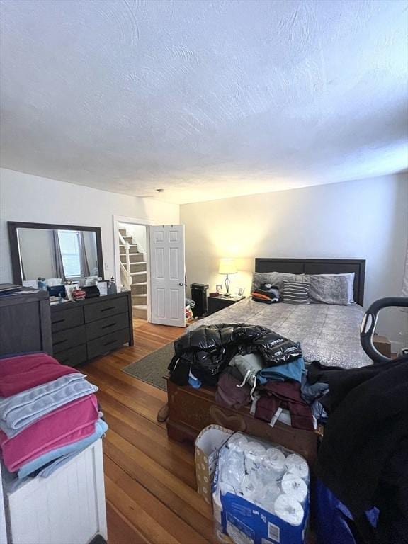 bedroom featuring a walk in closet, hardwood / wood-style flooring, a textured ceiling, and a closet