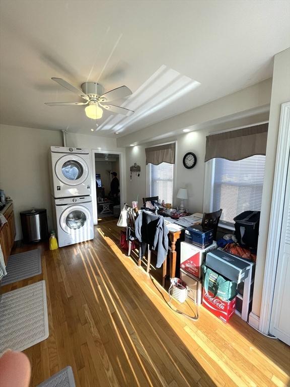 interior space featuring ceiling fan, stacked washing maching and dryer, and wood-type flooring