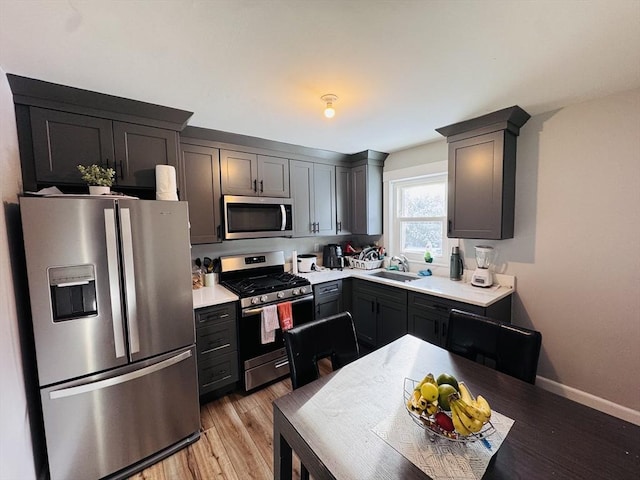 kitchen featuring stainless steel appliances, gray cabinets, sink, and light wood-type flooring