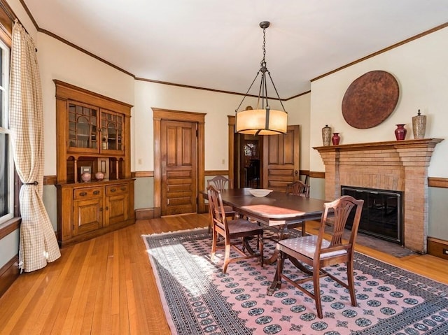 dining space with ornamental molding, a fireplace, and light hardwood / wood-style flooring