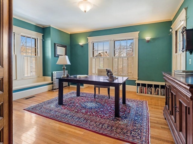 office with radiator heating unit, ornamental molding, and light wood-type flooring