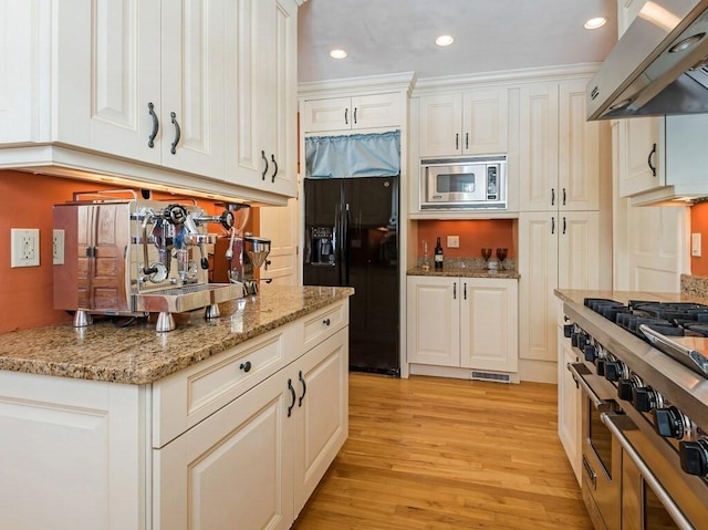 kitchen with light stone countertops, white cabinetry, appliances with stainless steel finishes, and exhaust hood