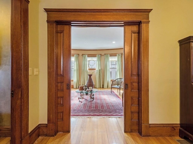 hallway featuring ornamental molding and light hardwood / wood-style floors