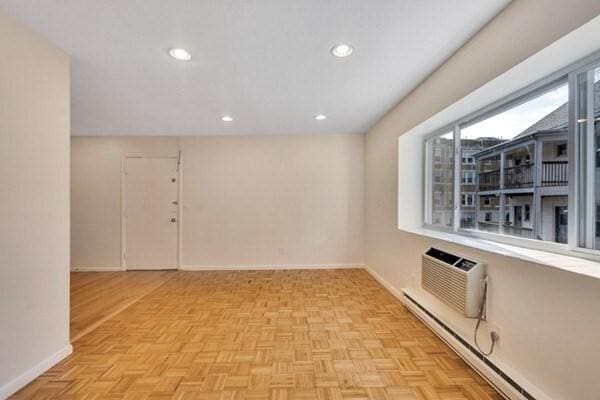 empty room featuring a baseboard radiator, a wall mounted AC, baseboards, and recessed lighting