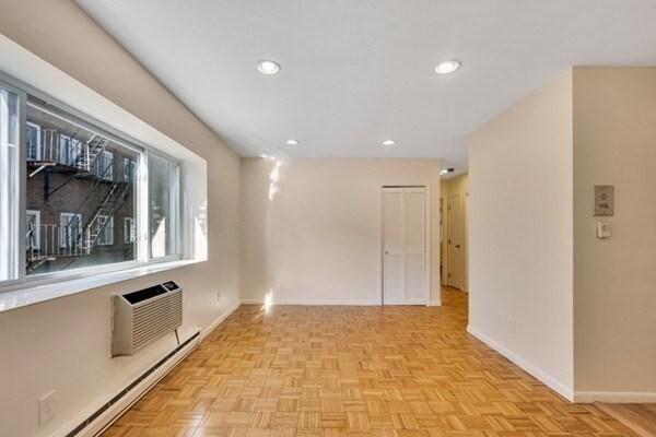 empty room featuring baseboard heating, a wall mounted AC, baseboards, and recessed lighting