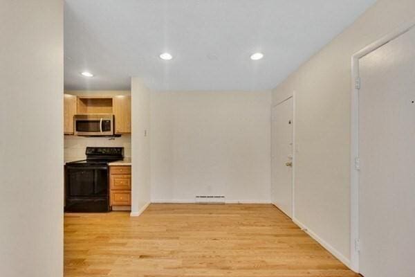 kitchen with black / electric stove, stainless steel microwave, recessed lighting, light wood-style flooring, and light countertops