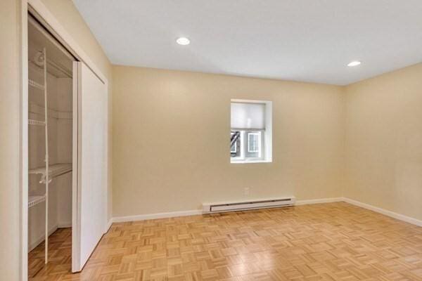 unfurnished bedroom with baseboard heating, a closet, recessed lighting, and baseboards
