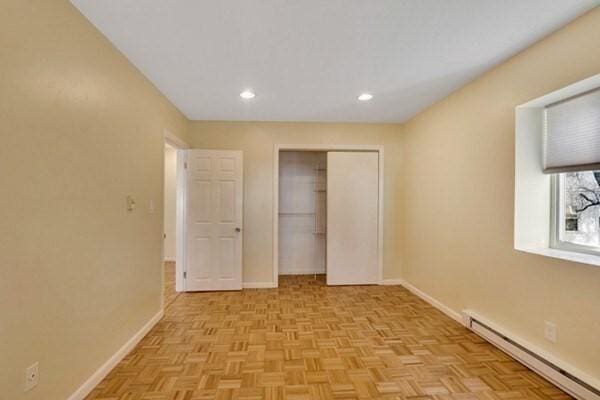 unfurnished bedroom with baseboard heating, baseboards, a closet, and recessed lighting