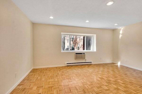 spare room featuring a baseboard heating unit, an AC wall unit, baseboards, and recessed lighting