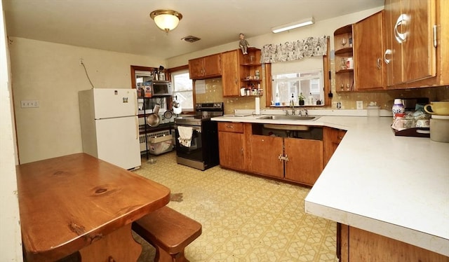 kitchen with stainless steel appliances, brown cabinets, light floors, and open shelves