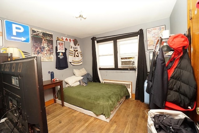 bedroom featuring radiator heating unit, baseboards, and wood finished floors