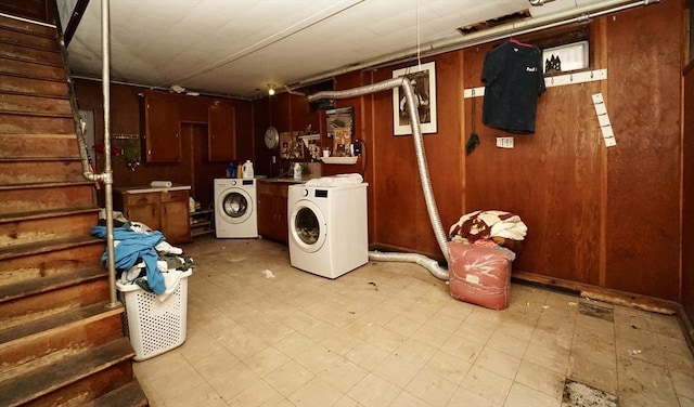 laundry area featuring laundry area, light floors, wood walls, and independent washer and dryer