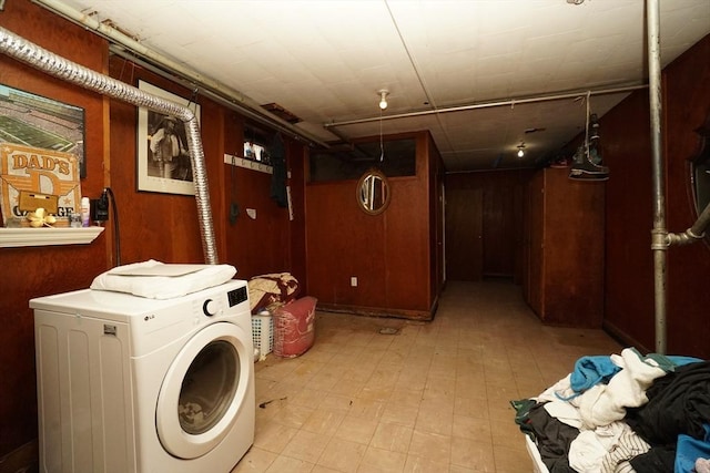 washroom with washer / clothes dryer, wood walls, and light floors