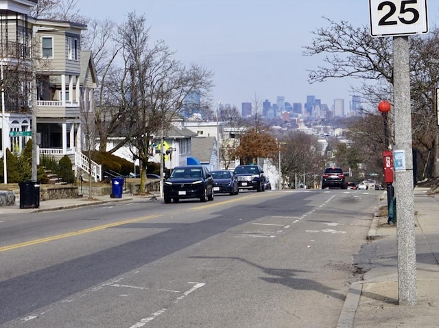 view of road featuring sidewalks, a city view, and curbs