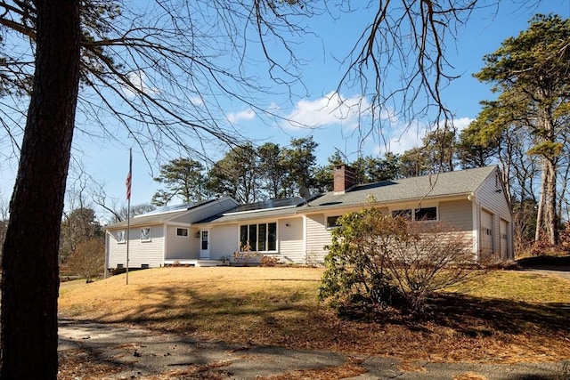 back of property featuring a garage and a yard