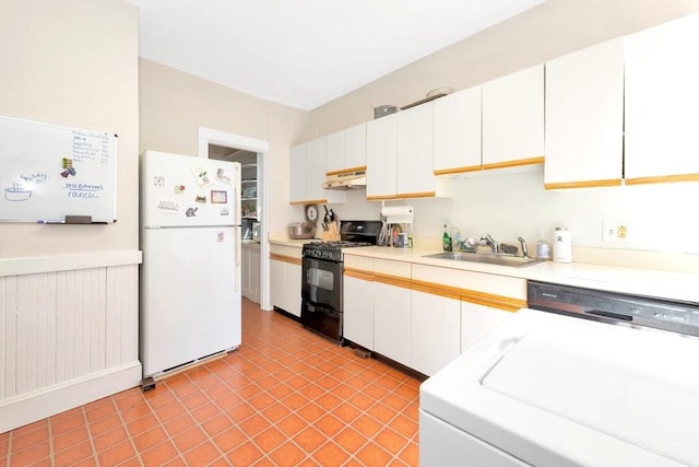 kitchen with freestanding refrigerator, black gas range, under cabinet range hood, a sink, and washer / clothes dryer