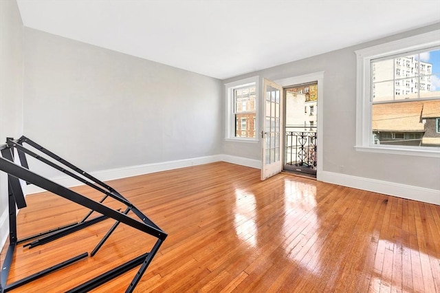 unfurnished room featuring baseboards, plenty of natural light, and hardwood / wood-style floors