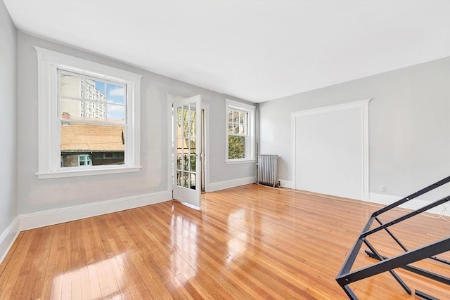 spare room with radiator, healthy amount of natural light, baseboards, and hardwood / wood-style flooring