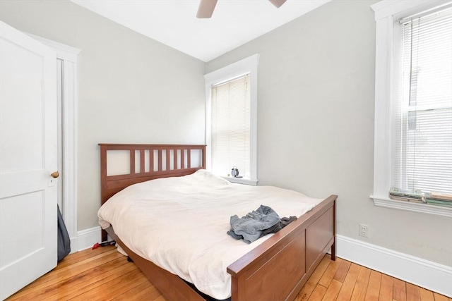 bedroom featuring light wood-type flooring, multiple windows, baseboards, and ceiling fan