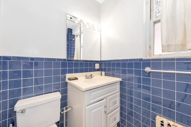 bathroom featuring tile walls, toilet, a wainscoted wall, and vanity