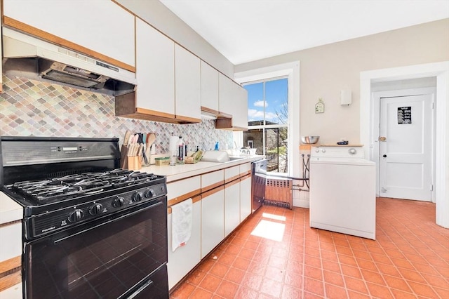 kitchen featuring black range with gas cooktop, washer / dryer, under cabinet range hood, and backsplash