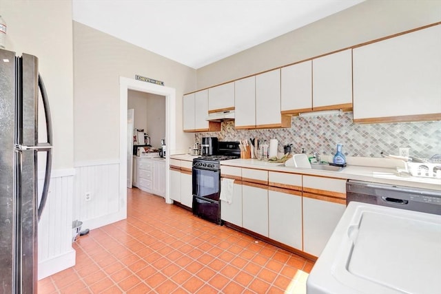 kitchen with black appliances, a sink, white cabinets, light countertops, and wainscoting