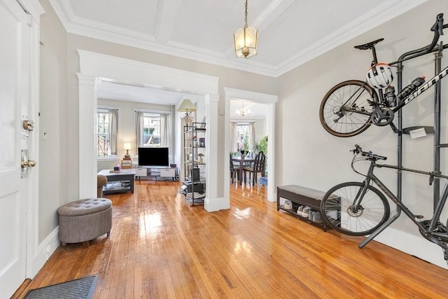 foyer with light wood finished floors, decorative columns, ornamental molding, and baseboards